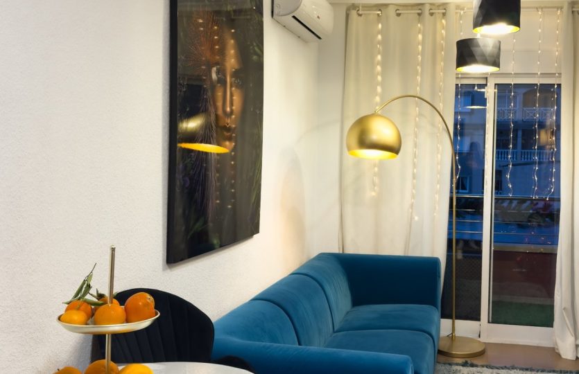 Rent in Torrevieja – Spacious Living Room with dining area, modern sofa, decorative lighting, Christmas tree, and access to the balcony.