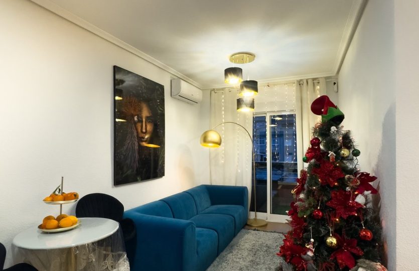 Rent in Torrevieja – Modern Living Room featuring a comfortable sofa, dining table, elegant lighting, air conditioning, and balcony access